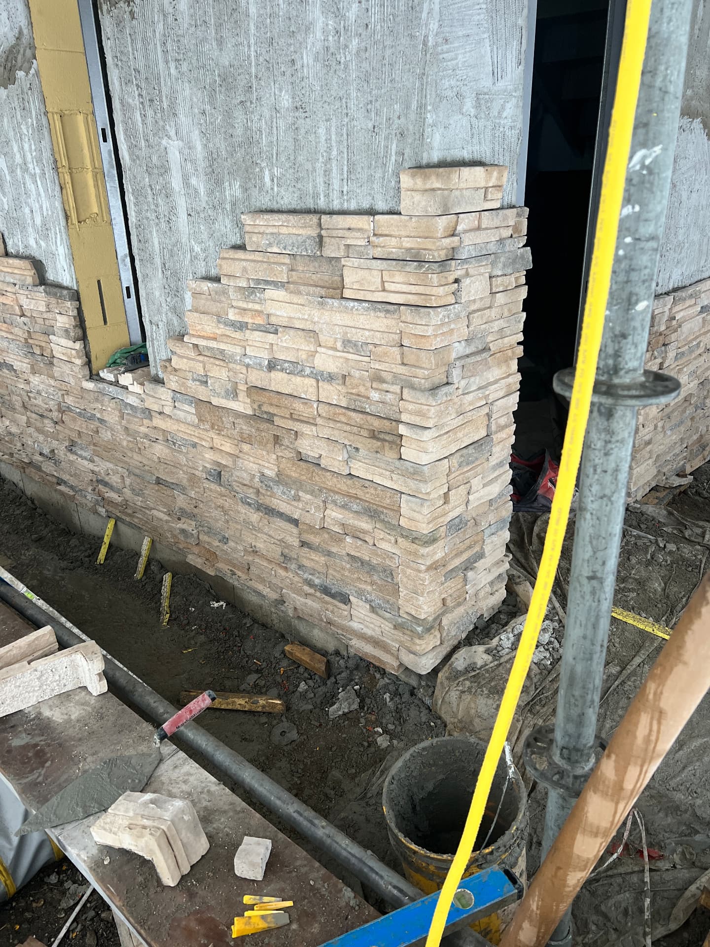 Stacked ledgestone veneer wall and pillar under construction