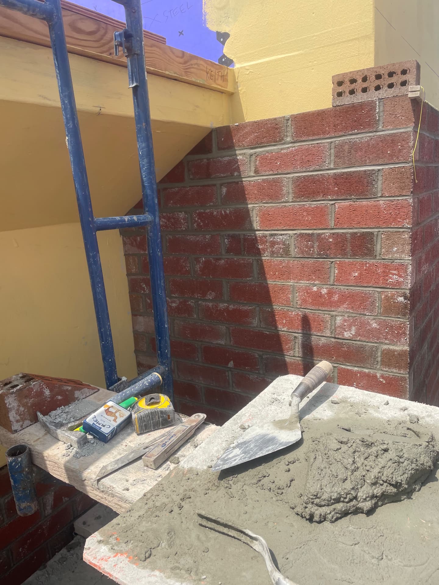 Brick wall in progress with trowel and mortar board