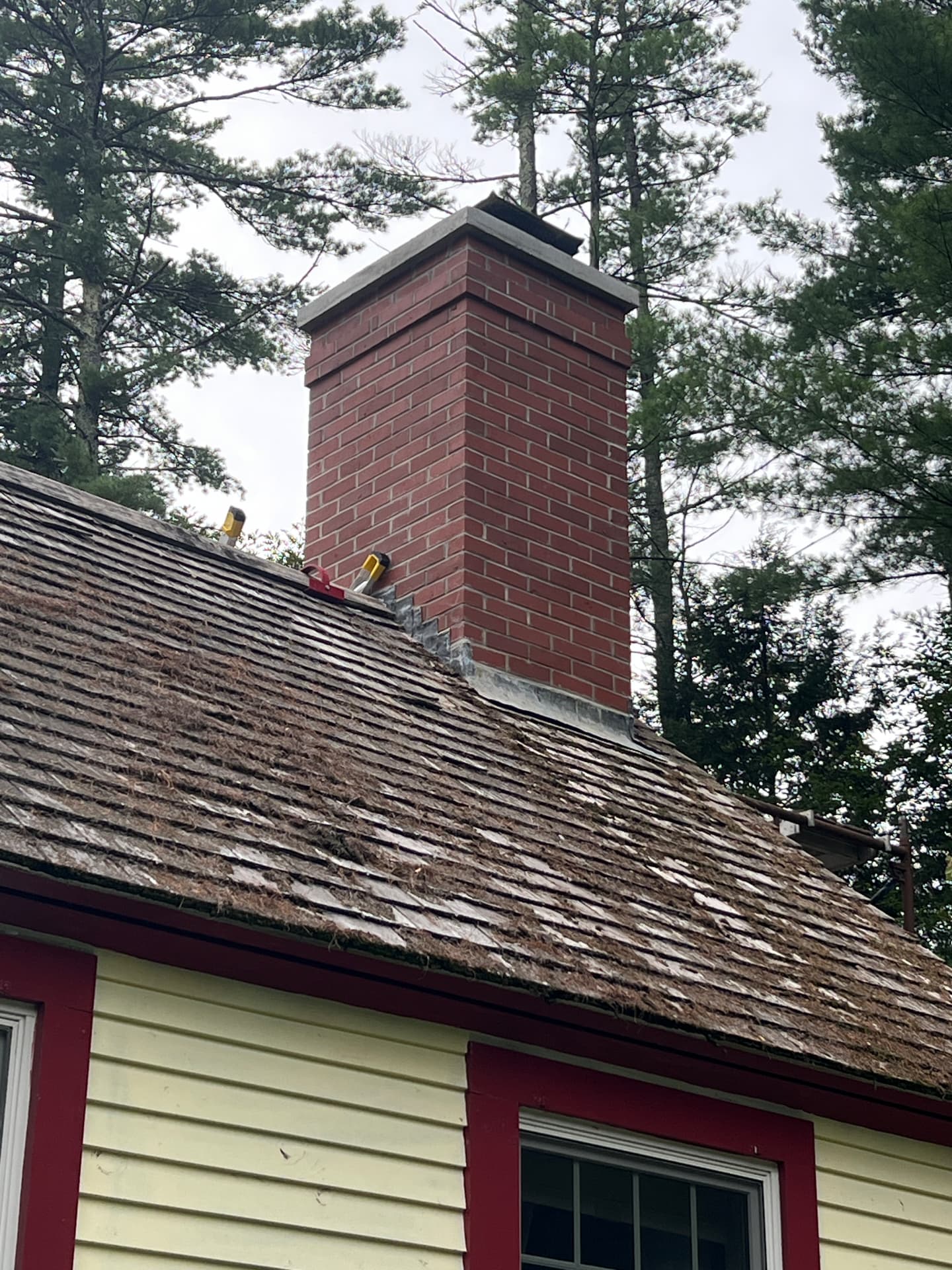 Finished red brick chimney on a shingle roof