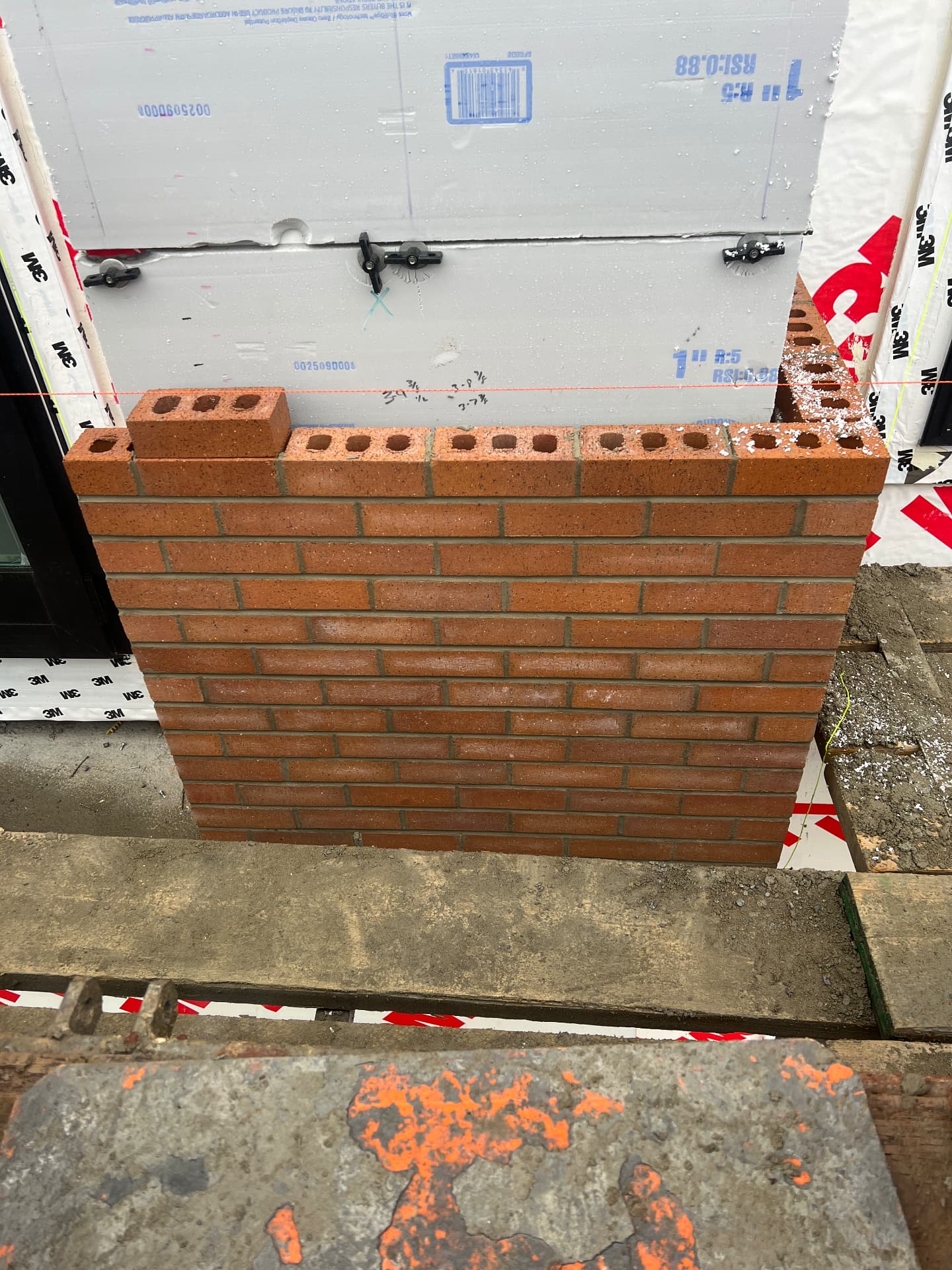 First courses of red brick veneer laid to a level line